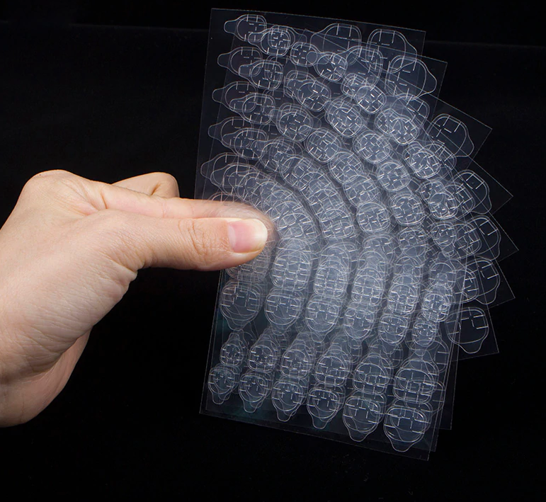 Plusieurs planches de pastilles adhésives transparentes tenues en éventail