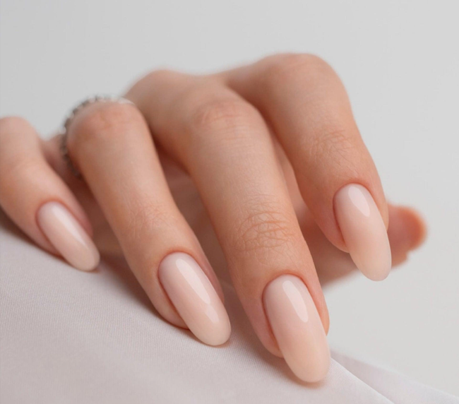 Main aux ongles en amande, manucure nude rosée