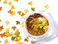 Pot de paillettes feuille d'érable or holographique et feuilles éparpillées