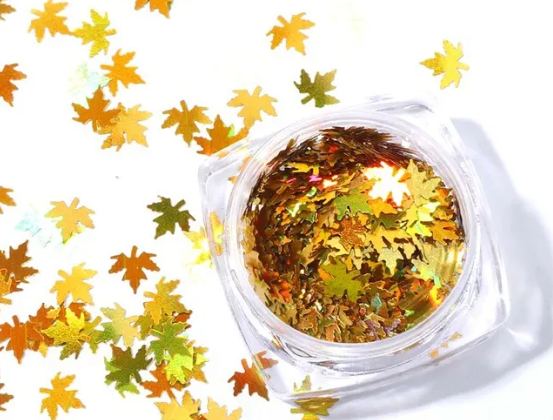 Pot de paillettes feuille d'érable or holographique et feuilles éparpillées